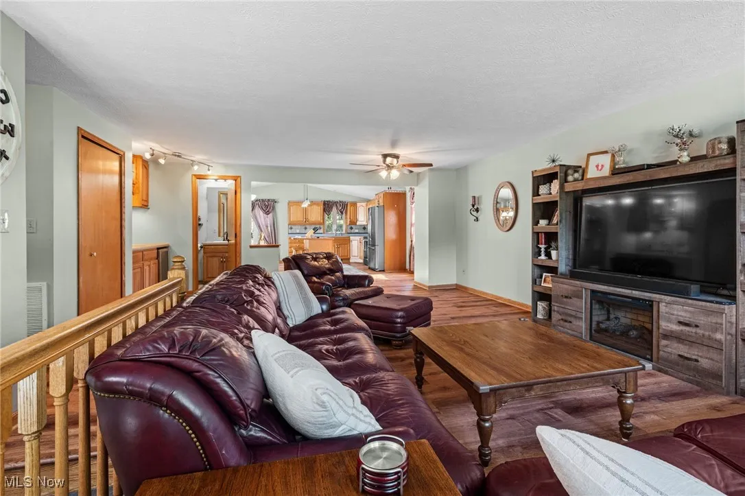 Living room featuring wood finished floors, ceiling fan, and a textured ceiling