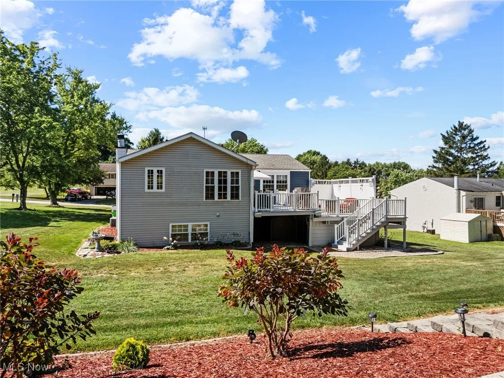 Rear view of property with a yard, a wooden deck, stairway, and a chimney