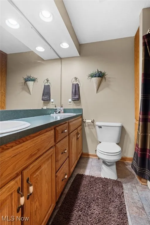 Bathroom with double vanity, recessed lighting, curtained shower, and light tile patterned floors