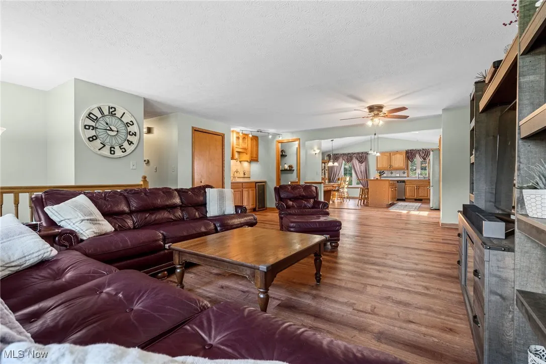 Living area featuring a chandelier, wood finished floors, a textured ceiling, wine cooler, and a ceiling fan