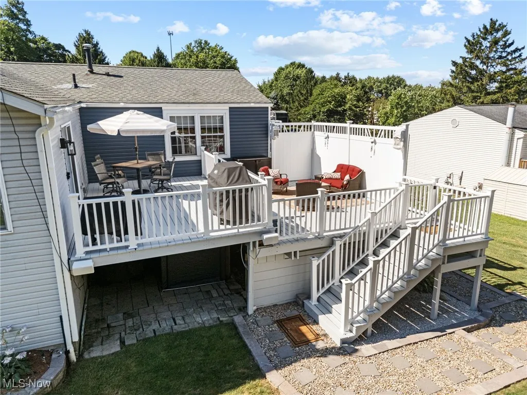 Back of property featuring roof with shingles, outdoor lounge area, a wooden deck, a garage, and stairs