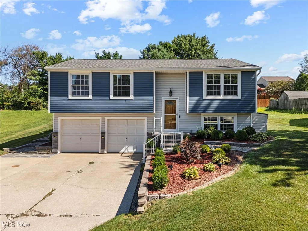 Split foyer home with a front yard, driveway, a garage, and a shingled roof