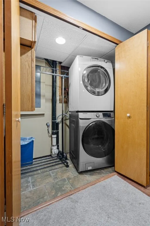 Laundry area with stacked washer / drying machine and stone finish flooring