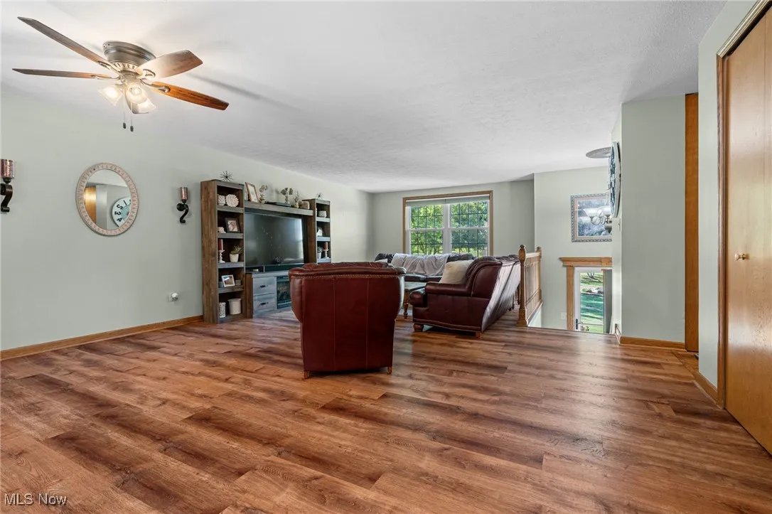 Living room with dark wood-style floors, a textured ceiling, and a ceiling fan