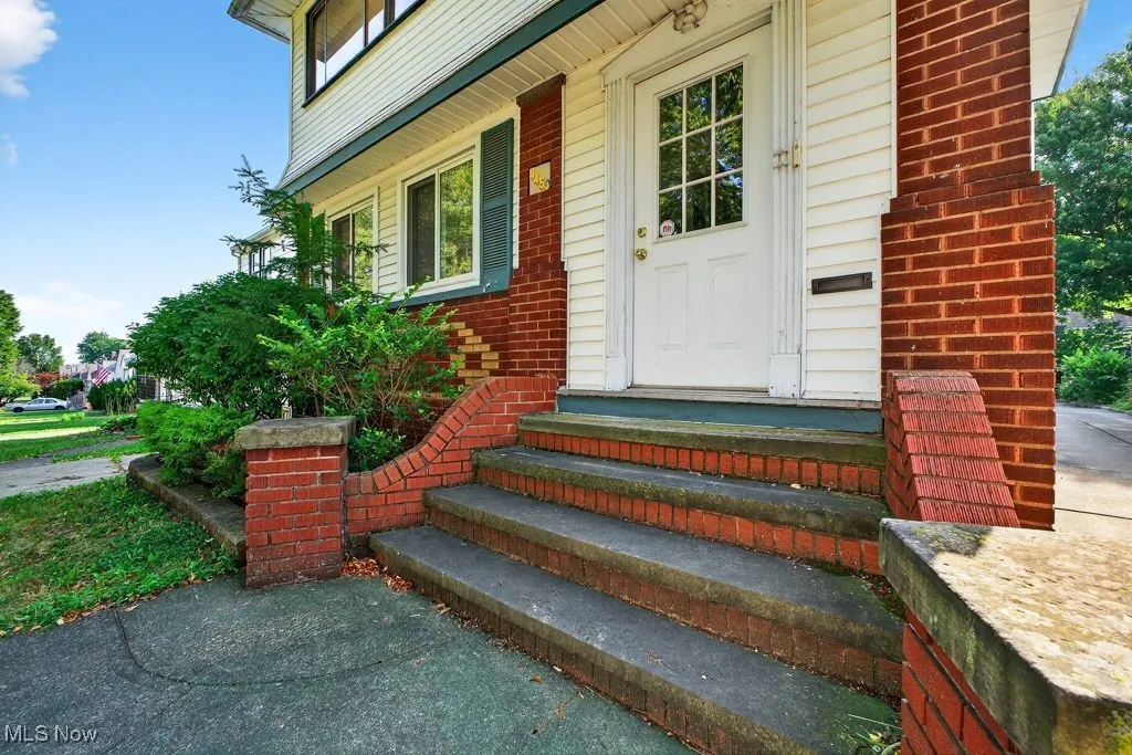 View of exterior entry with brick siding and covered porch