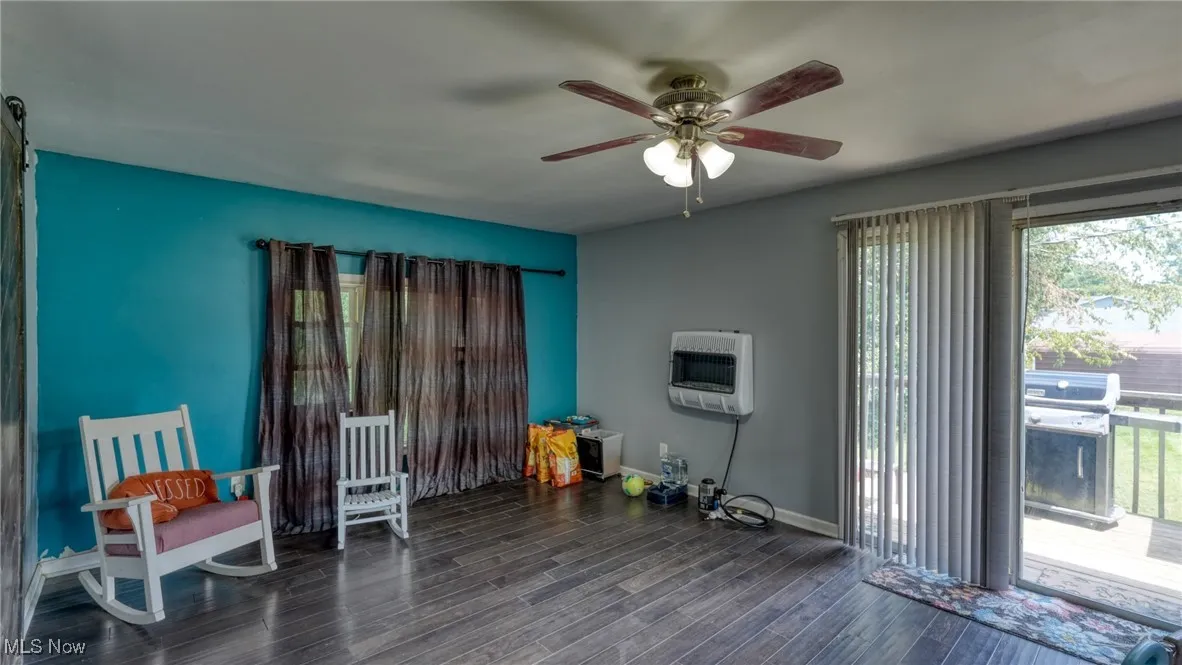 Living area with dark wood-type flooring, heating unit, and ceiling fan