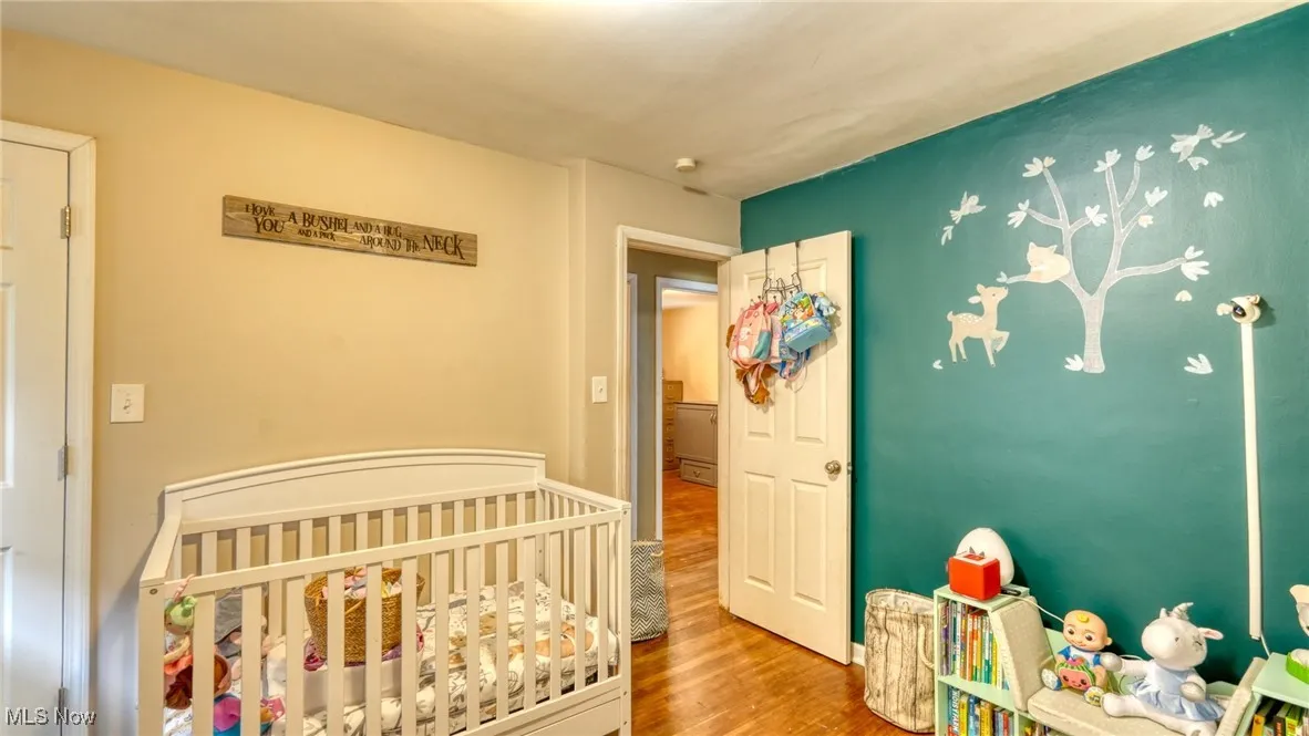 Bedroom with a crib and wood finished floors