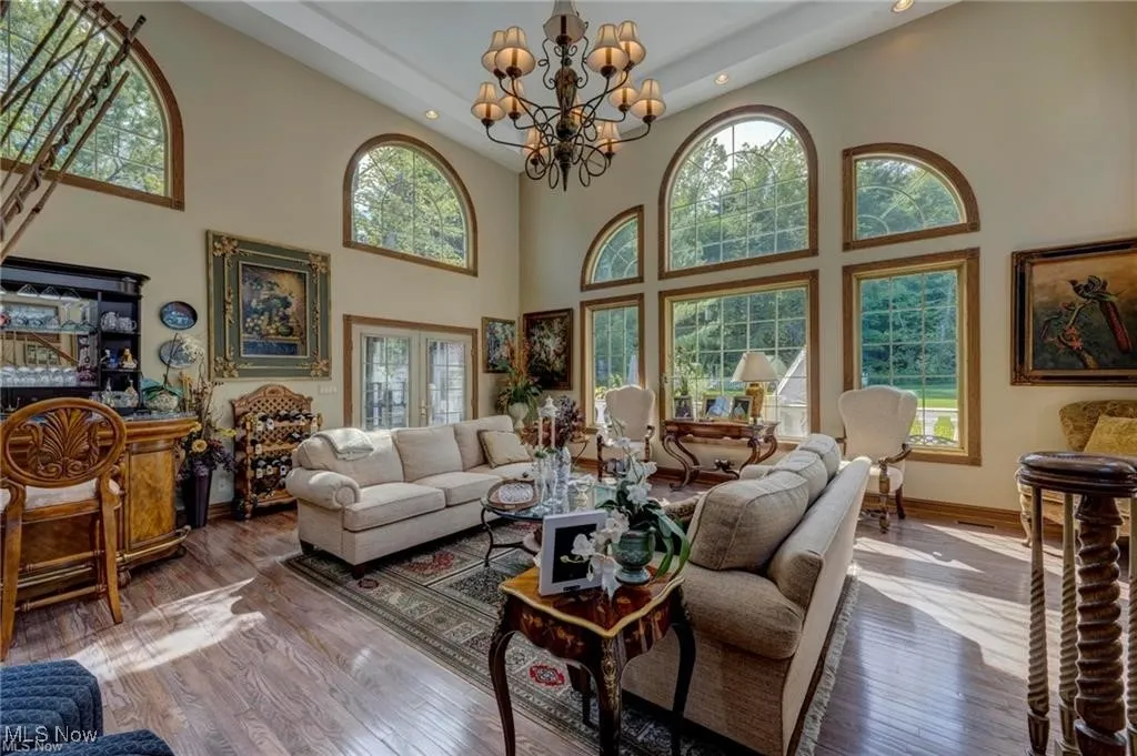 Living area featuring hardwood / wood-style flooring, a chandelier, plenty of natural light, recessed lighting, and a towering ceiling
