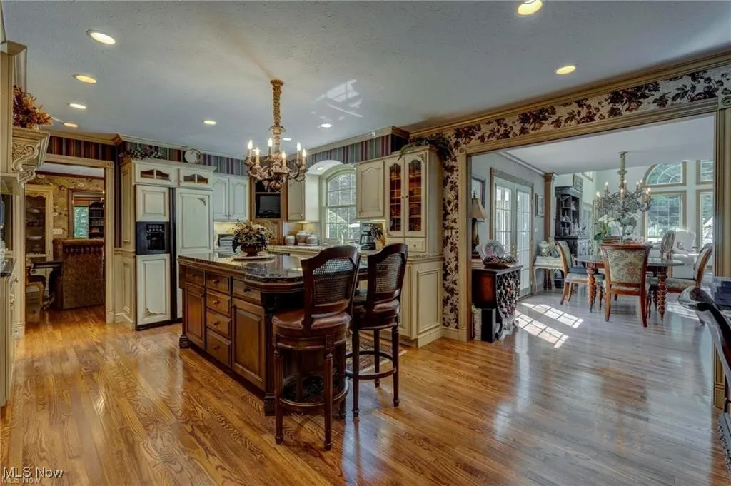 Kitchen with a chandelier, glass insert cabinets, a breakfast bar area, paneled fridge, and pendant lighting