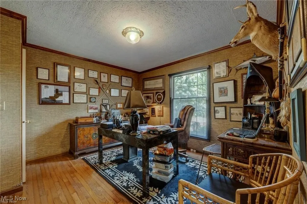 Office space featuring hardwood / wood-style floors, crown molding, wallpapered walls, and a textured ceiling