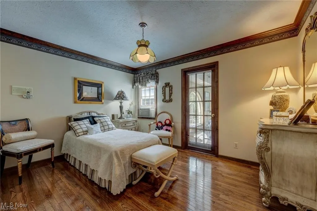 Bedroom featuring ornamental molding, a textured ceiling, and hardwood / wood-style floors