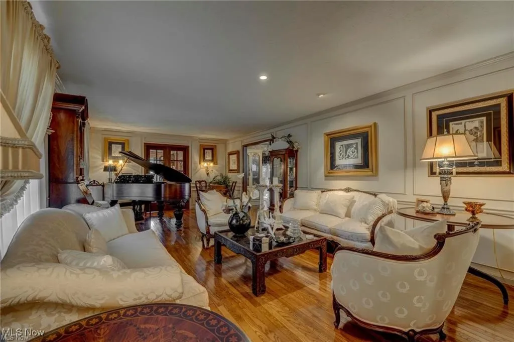 Living area with a decorative wall, wood finished floors, recessed lighting, and ornamental molding