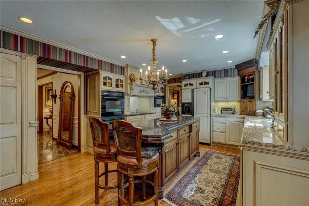 Kitchen with glass insert cabinets, light wood finished floors, paneled built in refrigerator, a center island, and recessed lighting