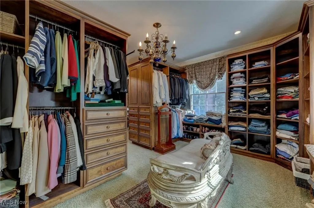 Master Walk in closet with a chandelier and light colored carpet