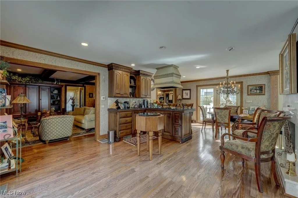 Prep area for entertaining featuring crown molding, dark countertops, light wood-style flooring, wallpapered walls, and a chandelier