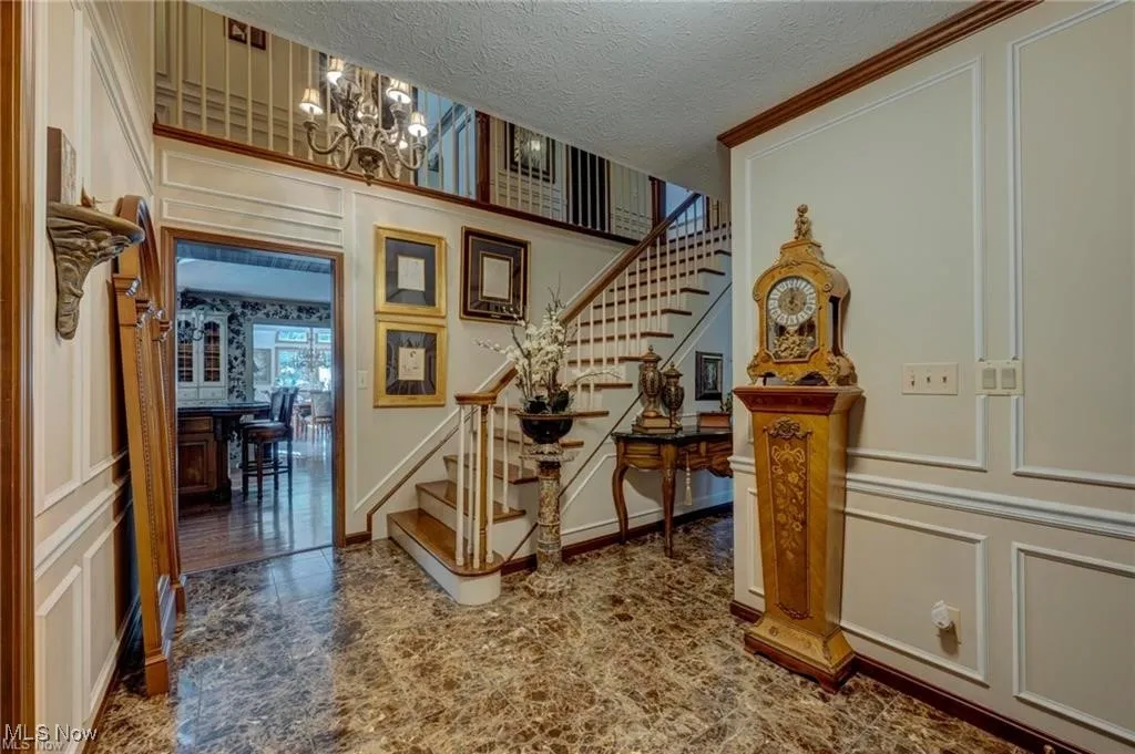 Stairway featuring a decorative wall, a textured ceiling, and a chandelier