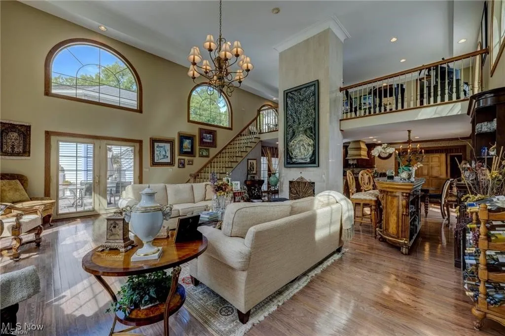 Living area with a chandelier, stairs, a towering ceiling, wood finished floors, and recessed lighting
