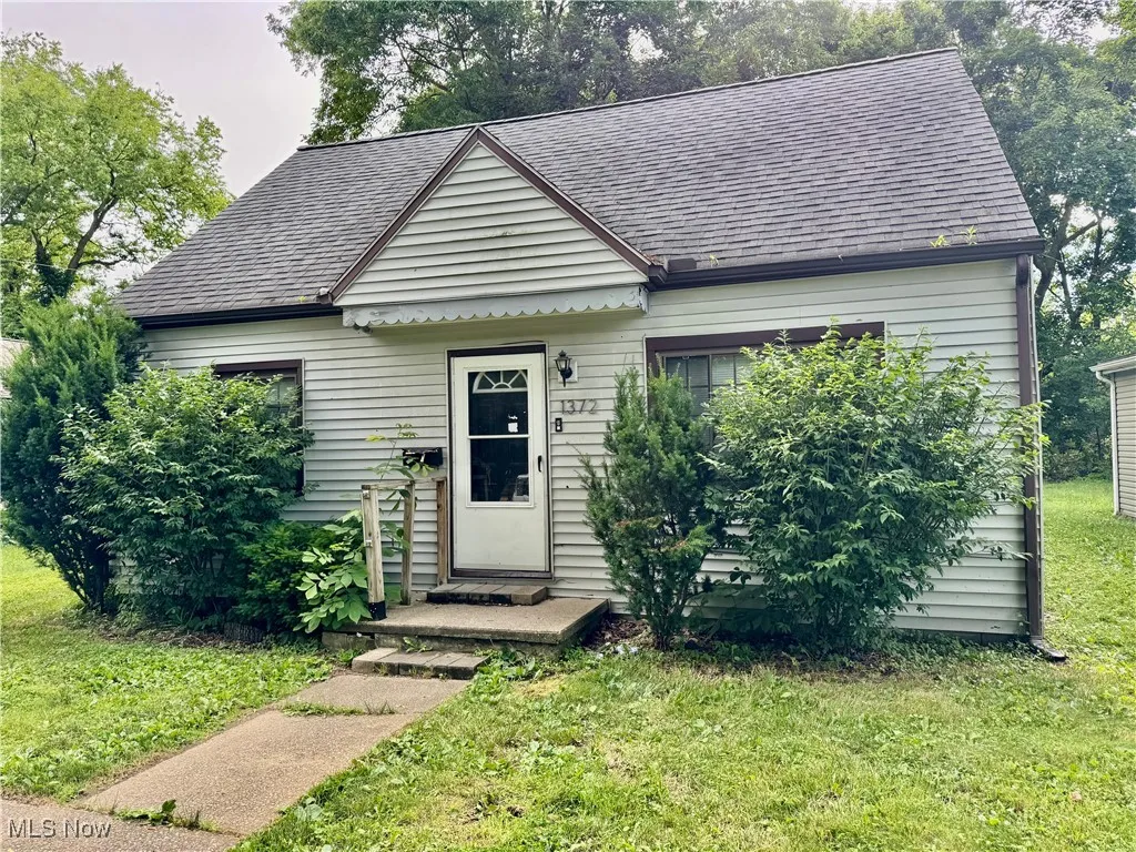 View of front facade with a front yard and roof with shingles
