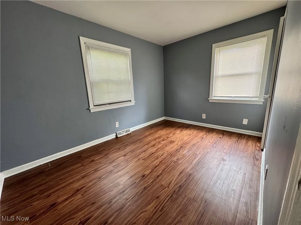 Unfurnished room with dark wood finished floors and healthy amount of natural light