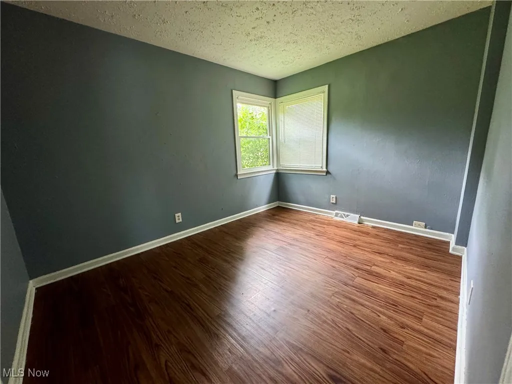 Empty room with wood finished floors and a textured ceiling
