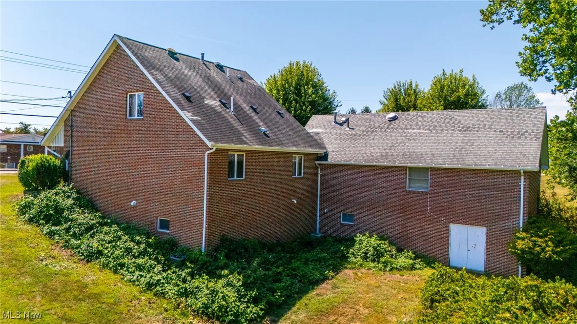Rear view of property with crawl space and brick siding