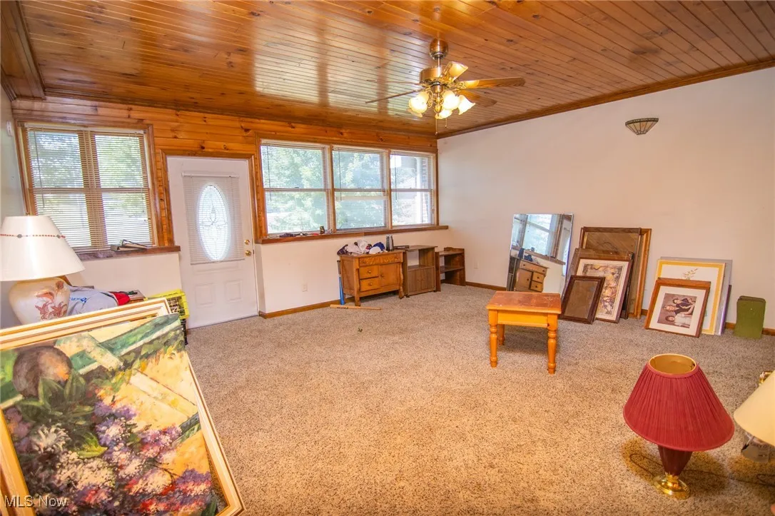 Recreation room featuring wooden ceiling, carpet, ornamental molding, and ceiling fan