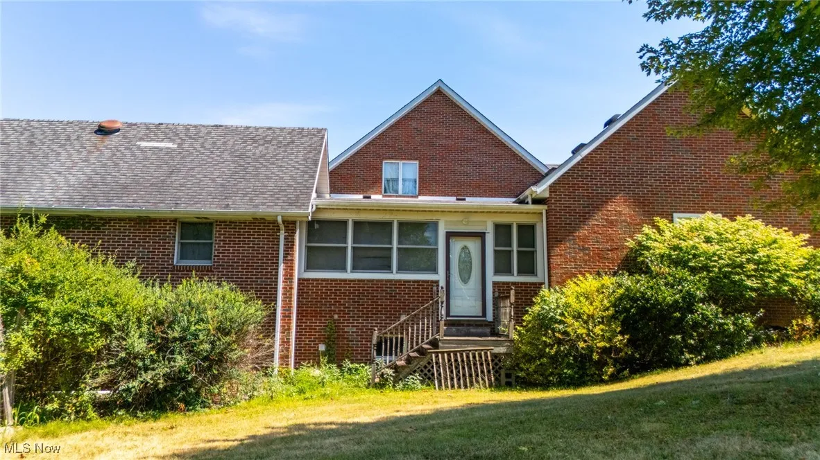 View of front of house with brick siding, a front lawn, a shingled roof, and a sunroom
