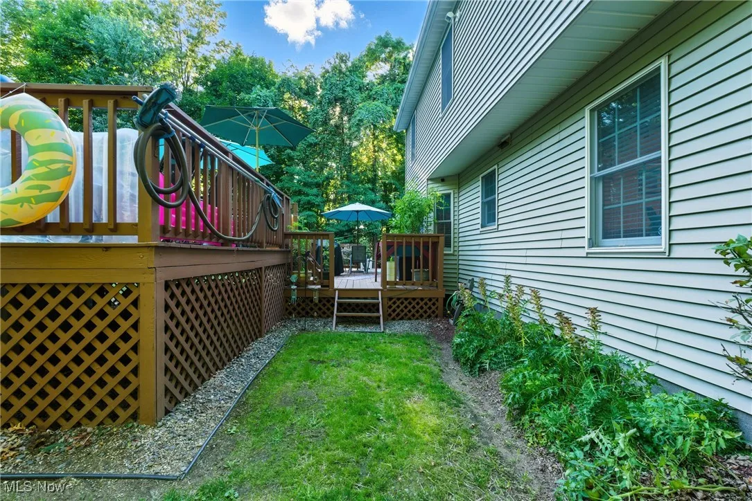 View of side of property with a deck and a lawn