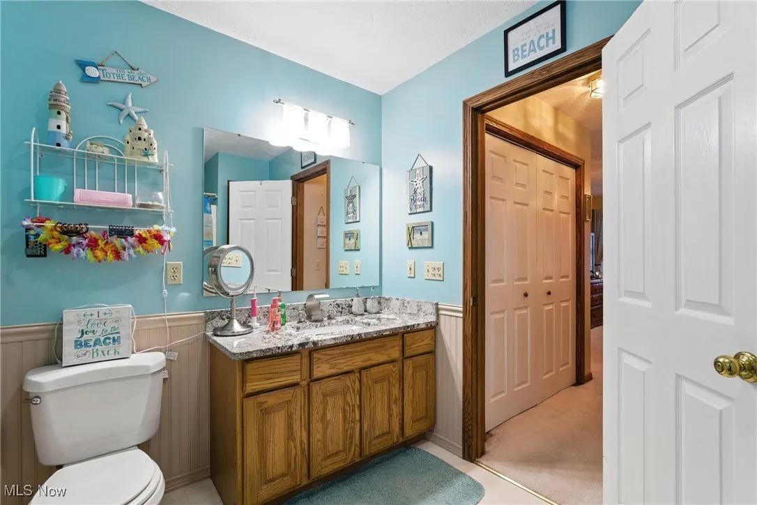 Bathroom featuring a wainscoted wall, vanity, and a closet