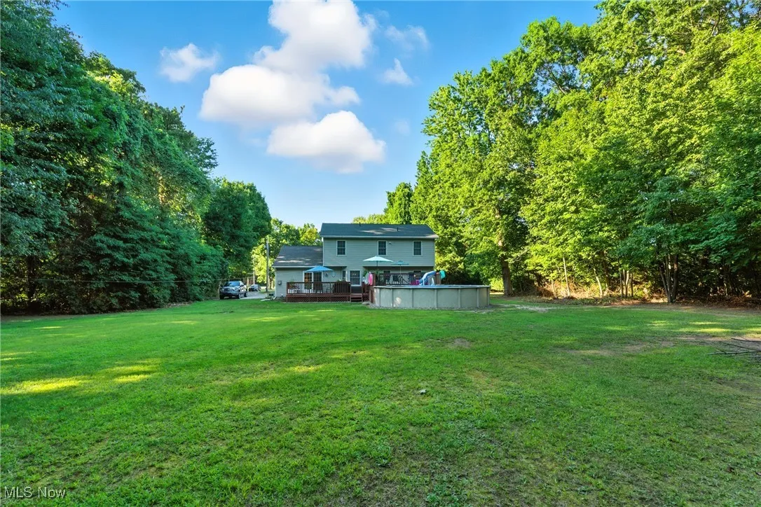 View of green lawn with an outdoor pool and a deck