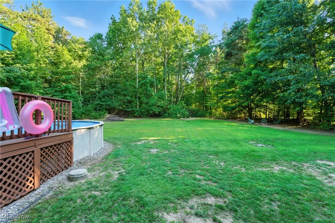 View of green lawn with a deck and an outdoor pool