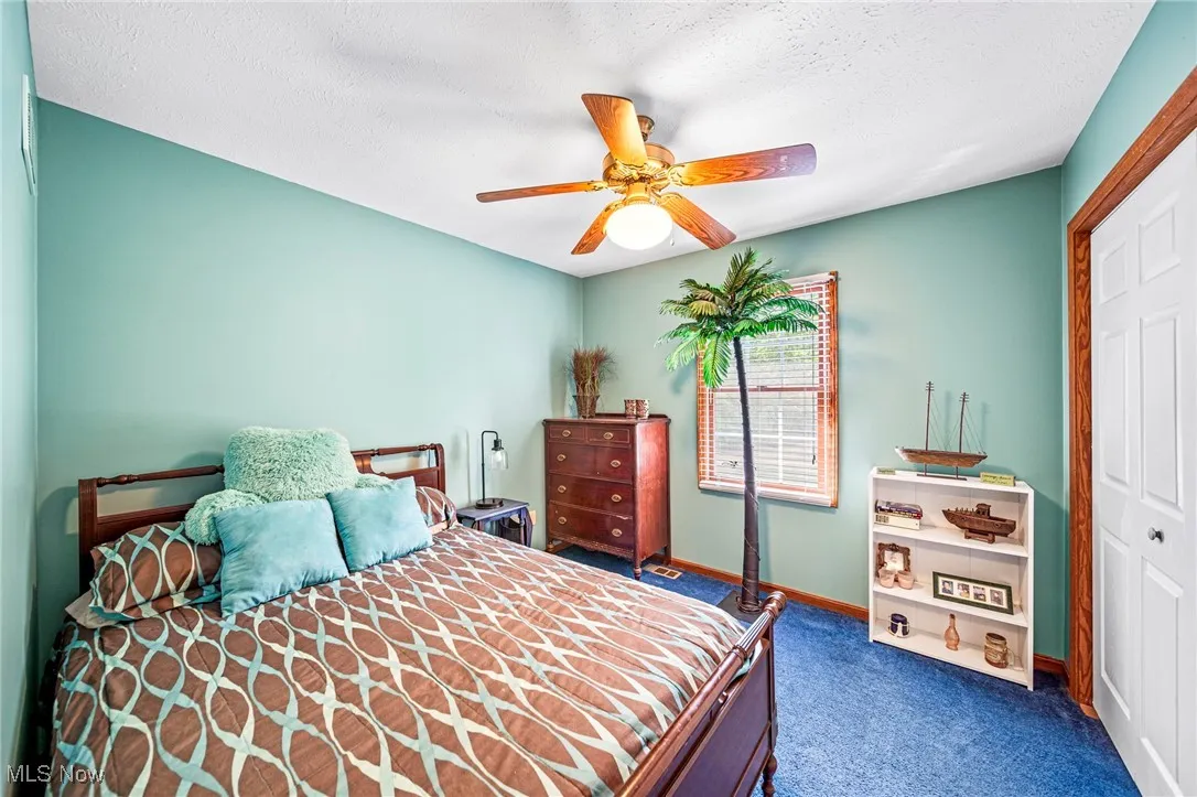 Bedroom featuring a closet, dark carpet, a textured ceiling, and a ceiling fan
