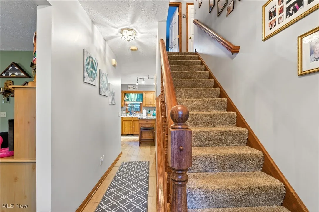 Stairs featuring a textured ceiling and wood finished floors