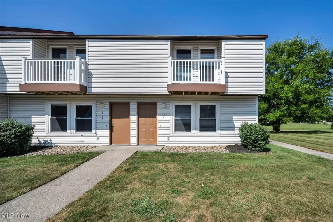 View of front of property with a balcony and a front yard