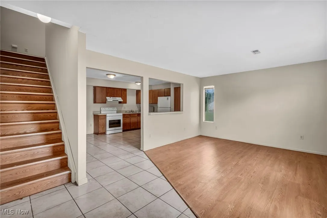 Unfurnished living room with light tile patterned floors and stairway