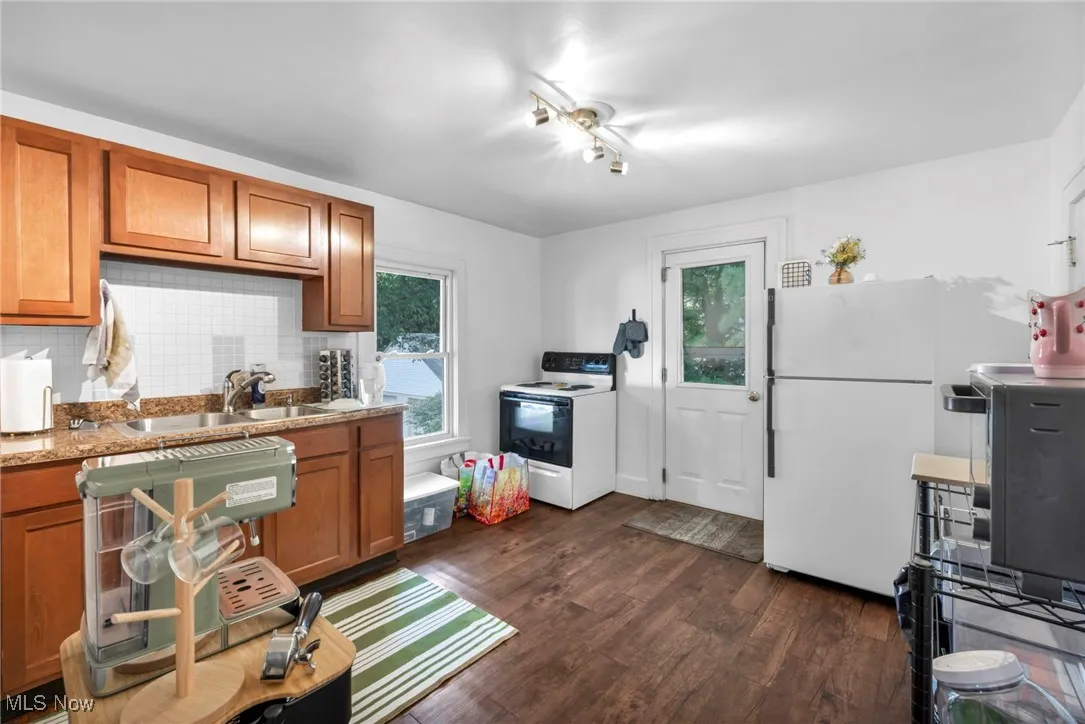 Kitchen featuring brown cabinetry, white appliances, tasteful backsplash, and plenty of natural light