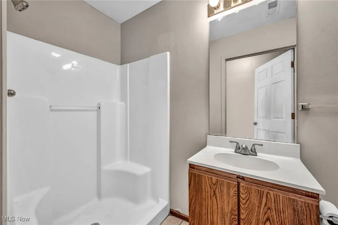Bathroom with a shower stall, vanity, and light tile patterned floors