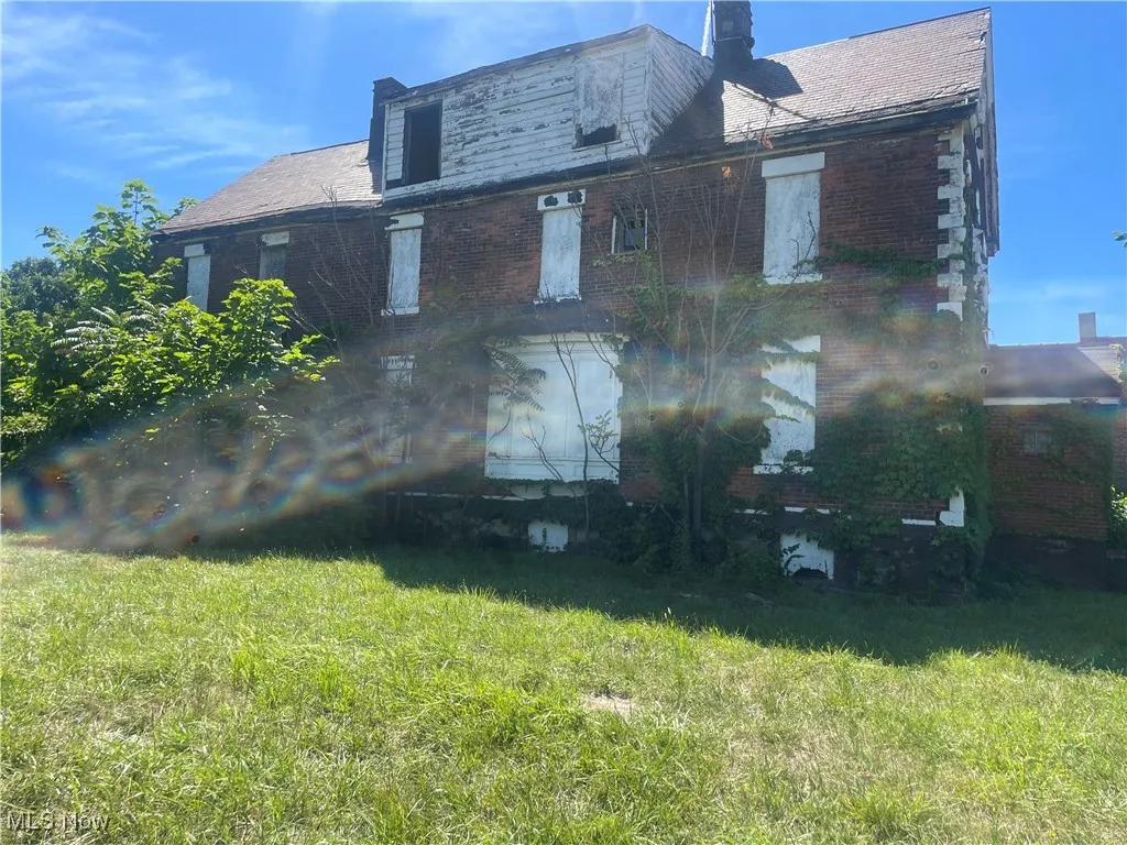 Back of property with a chimney, brick siding, and a lawn