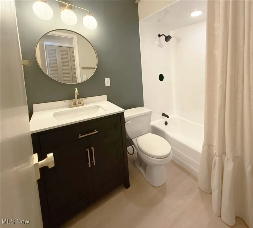 Bathroom with shower / bath combo with shower curtain, light wood finished floors, vanity, and a closet