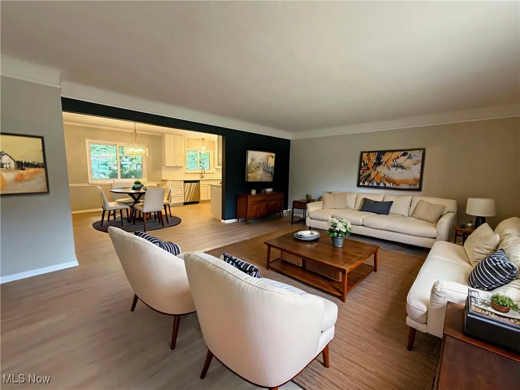 Living room with light wood-type flooring, a chandelier, and crown molding