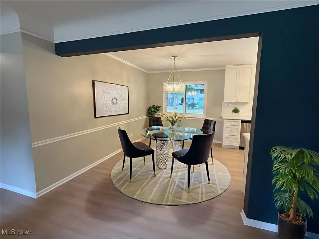 Dining space featuring ornamental molding, light wood-style flooring, and a chandelier