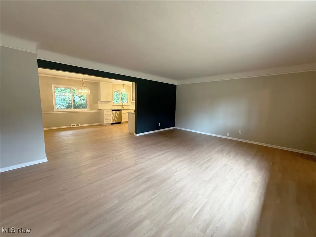 Spare room featuring light wood-style flooring, a chandelier, and ornamental molding
