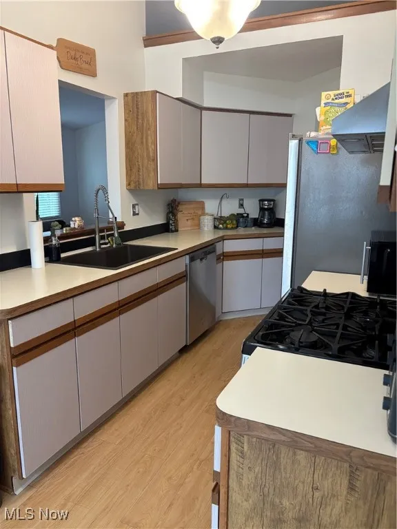 Kitchen featuring range, light wood-style flooring, exhaust hood, light countertops, and brown cabinetry