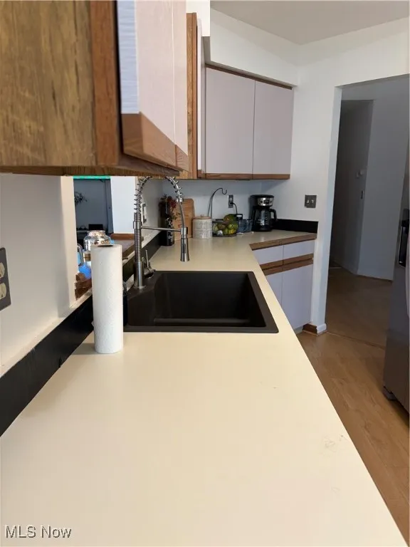 Kitchen featuring wood finished floors, light countertops, fridge, and brown cabinetry