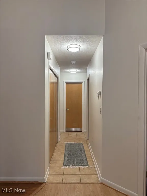 Hallway featuring a textured ceiling and light wood finished floors
