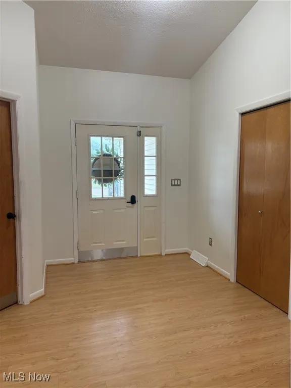 Foyer with light wood-style floors and a textured ceiling
