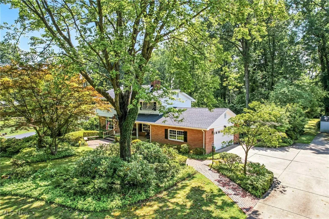 View of front of house featuring roof with shingles, driveway, brick siding, a porch, and a garage