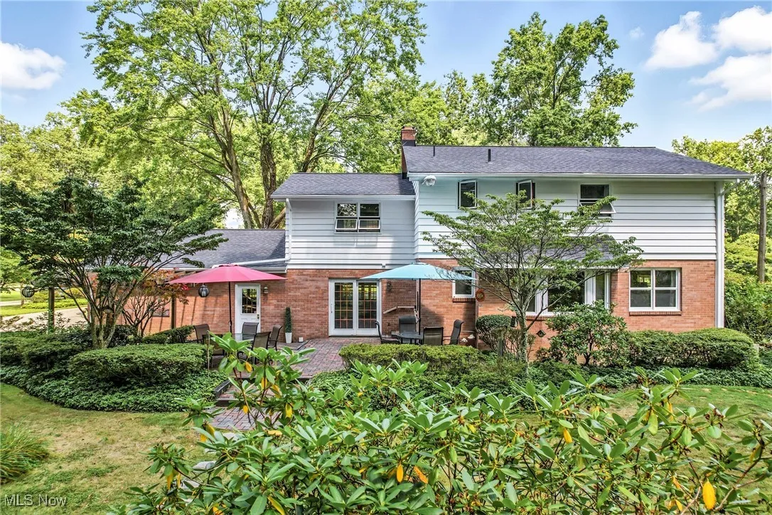 Back of property with brick siding, a chimney, and a patio area