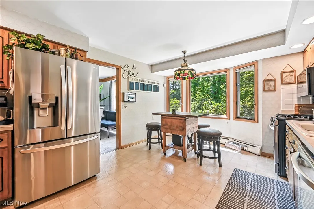 Kitchen featuring appliances with stainless steel finishes, brown cabinets, and hanging light fixtures