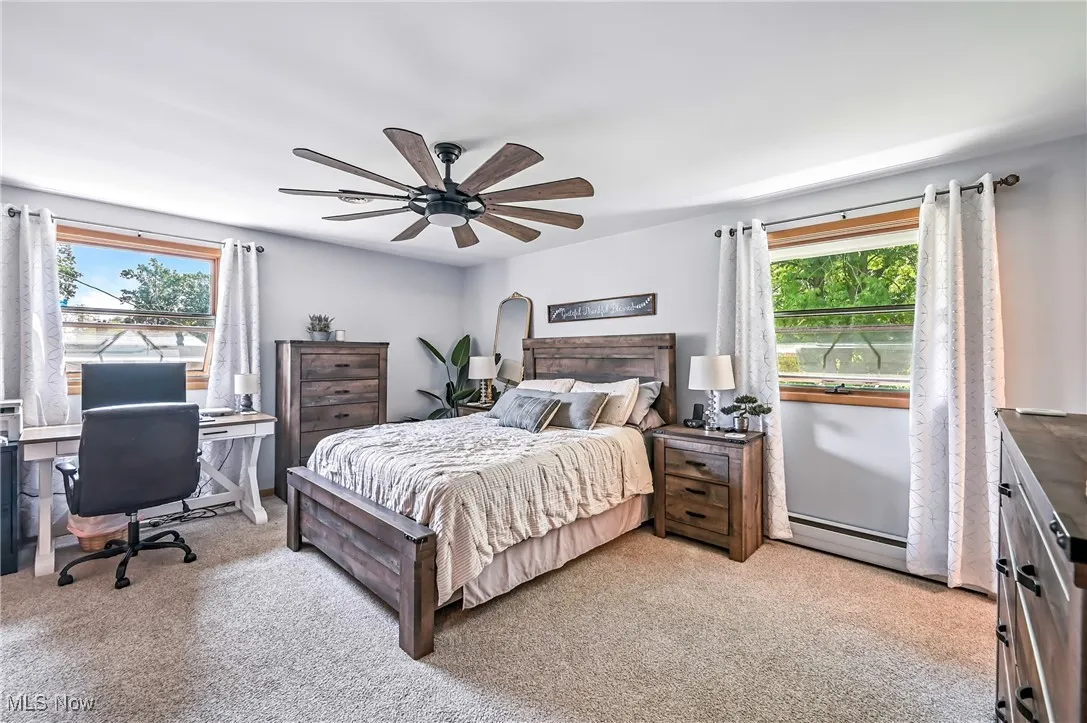 Bedroom with light colored carpet, a ceiling fan, and baseboard heating